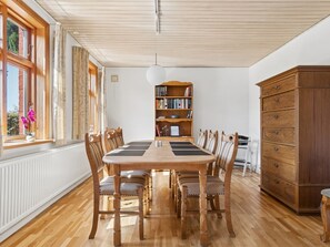 Ein Esszimmer mit einem Holztisch, Stühlen, einem Bücherregal und einem Schrank.