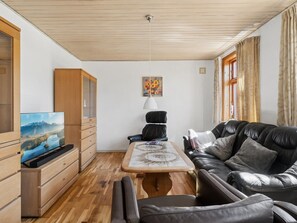 A modern living room with a wooden ceiling, a flat-screen TV, a sofa, a table, and a cabinet. - "Helge" - 10km from the sea by Interhome (Rønne)