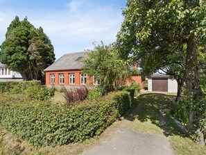 Ein Wohnhaus mit roter Ziegel Fassade, einer Auffahrt und einem gepflegten Garten.