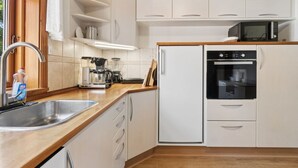 A modern kitchen with white cabinets, a stainless steel sink, a microwave, and an oven. - "Helge" - 10km from the sea by Interhome (Rønne)