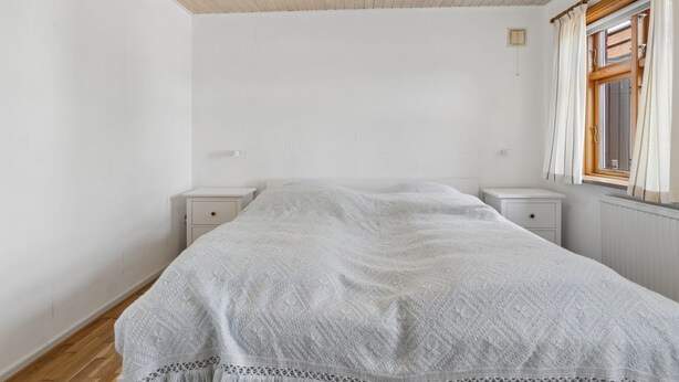 A bedroom with a bed, two bedside tables, a window with curtains, and a wooden ceiling. - "Helge" - 10km from the sea by Interhome (Rønne)