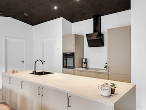 Una cocina moderna con una isla central, horno empotrado y campana extractora negra.