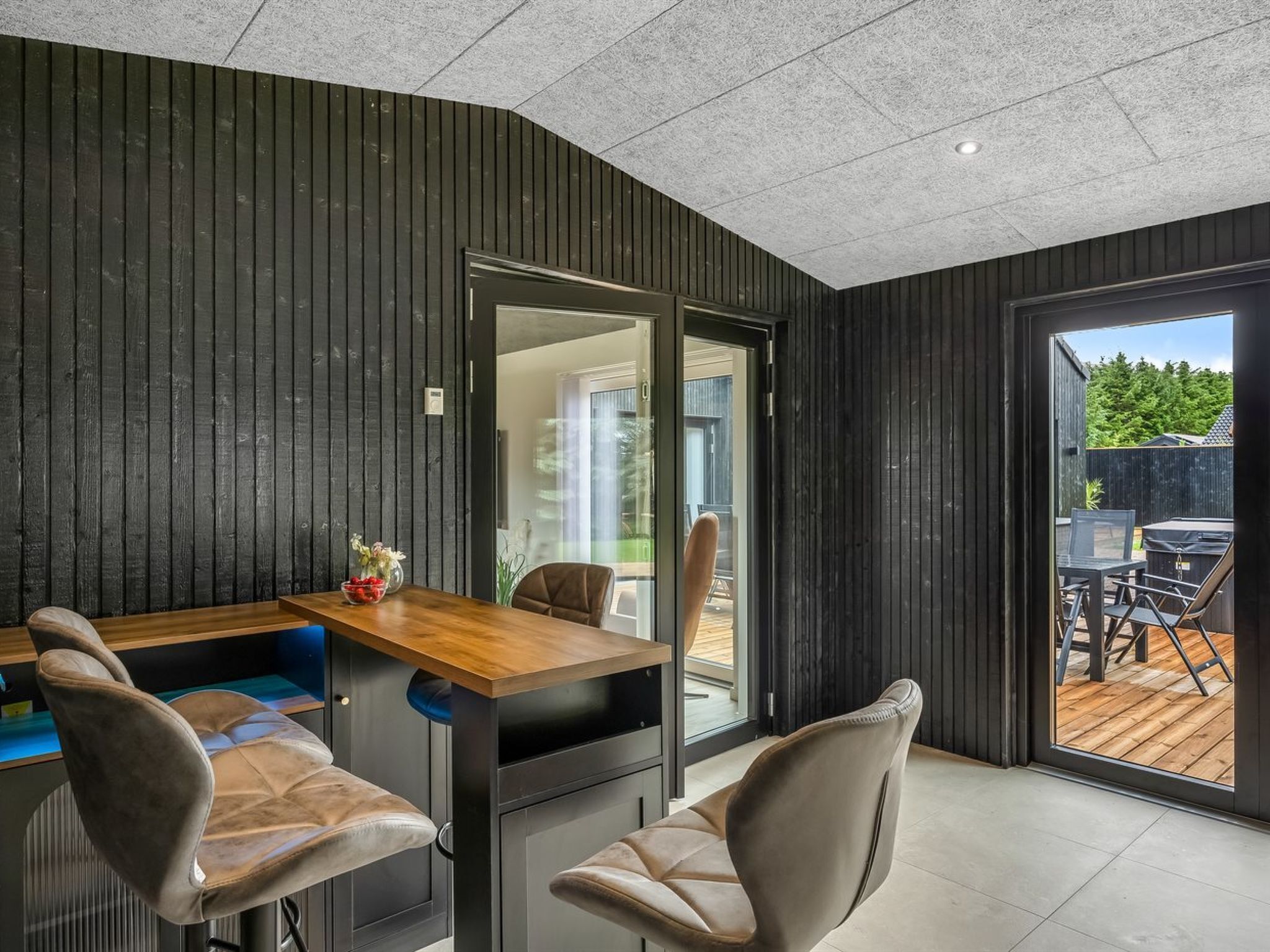 Een modern interieur met een eethoek, twee stoelen, een tafel en een glazen schuifdeur naar een terras.