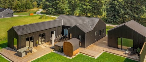 Een modern gebouw met een plat dak, grote ramen en een houten terras.