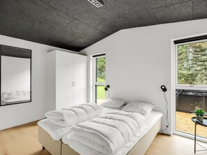 A modern bedroom with a large bed, a wardrobe, and a window with a view of trees. - "Lillesol" - 1.3km from the sea by Interhome (Hjørring)