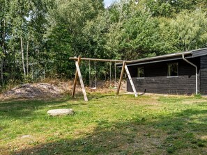 A wooden swing set in a grassy area with a wooden cabin in the background. - "Nakke" - 900m from the sea by Interhome (Hadsund)