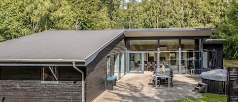 A modern house with a flat roof, large windows, and a patio with outdoor furniture.