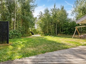 A wooden deck leading to a grassy area with a swing set and a black gate. - "Nakke" - 900m from the sea by Interhome (Hadsund)
