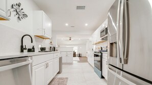 A modern kitchen with white cabinetry, stainless steel appliances, and a central island.