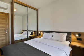 A hotel room with a large bed, wooden headboard, bedside tables, and a mirror.