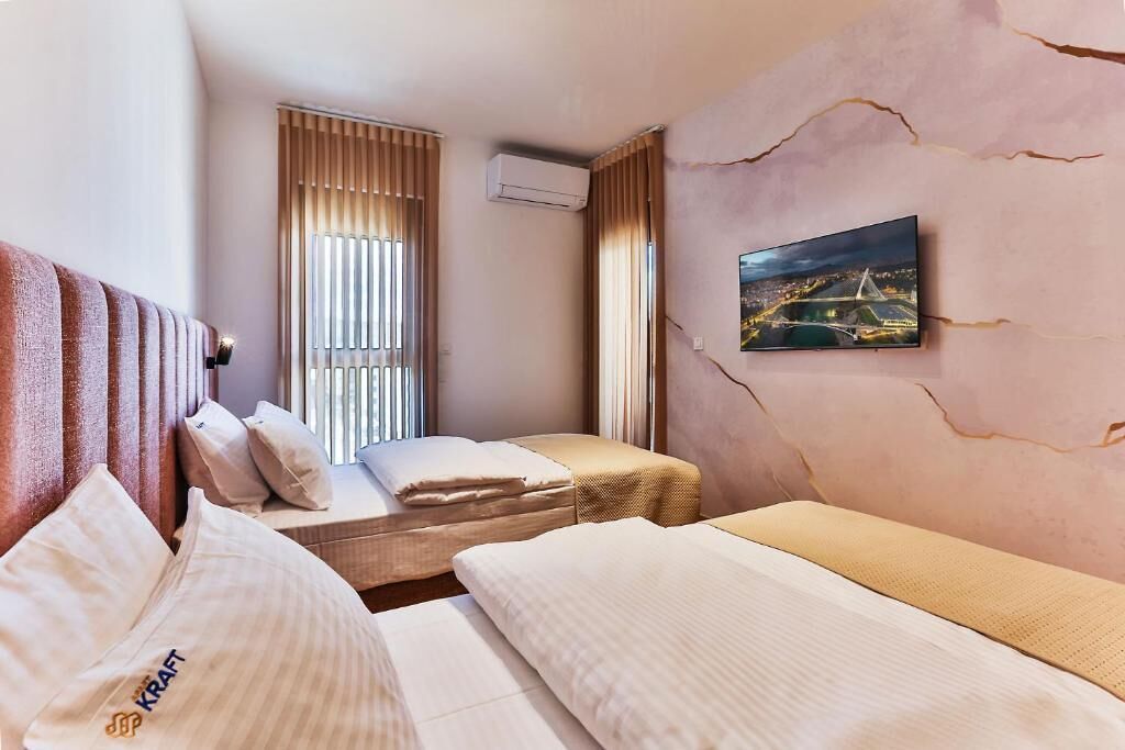 Ein Hotelzimmer mit Bett, einem Fenster mit Jalousien, einer Klimaanlage und einem Bild an der Wand.