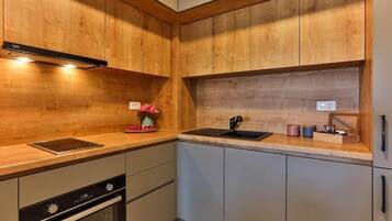 Cocina moderna con armarios de madera, horno empotrado, un lavamanos y una encimera con un florero y utensilios.