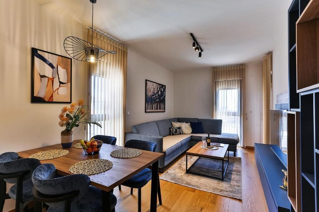 A modern living room with a sofa, dining table, and chairs, a coffee table, and artwork on the walls.