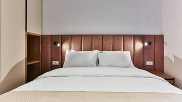 A neatly made bed with a wooden headboard, two bedside tables, and a wall-mounted light fixture.
