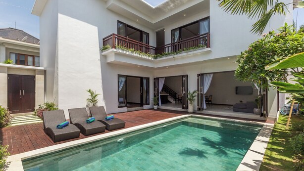 A modern two-story house with a swimming pool, outdoor furniture, and a balcony with plants. - Villa Azura Seminyak (Badung)