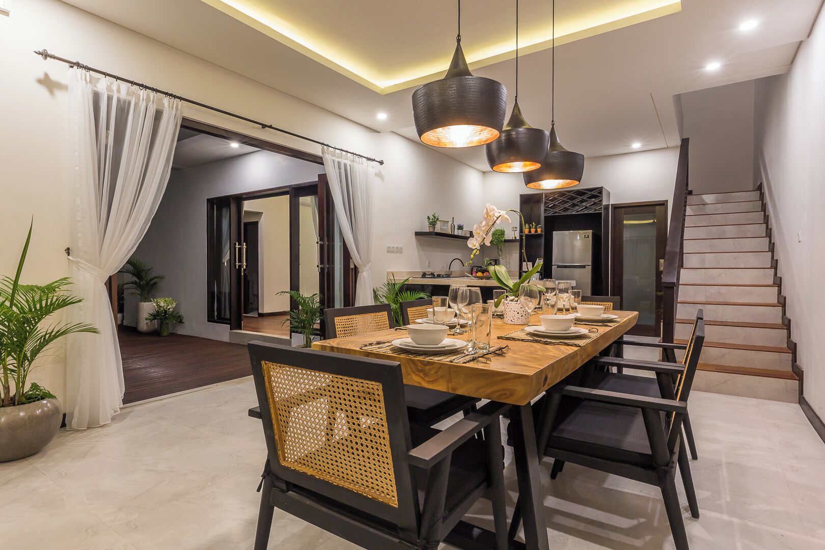 Comedor con una mesa de madera dispuesta para cuatro personas, rodeada de sillas con respaldo de mimbre.
