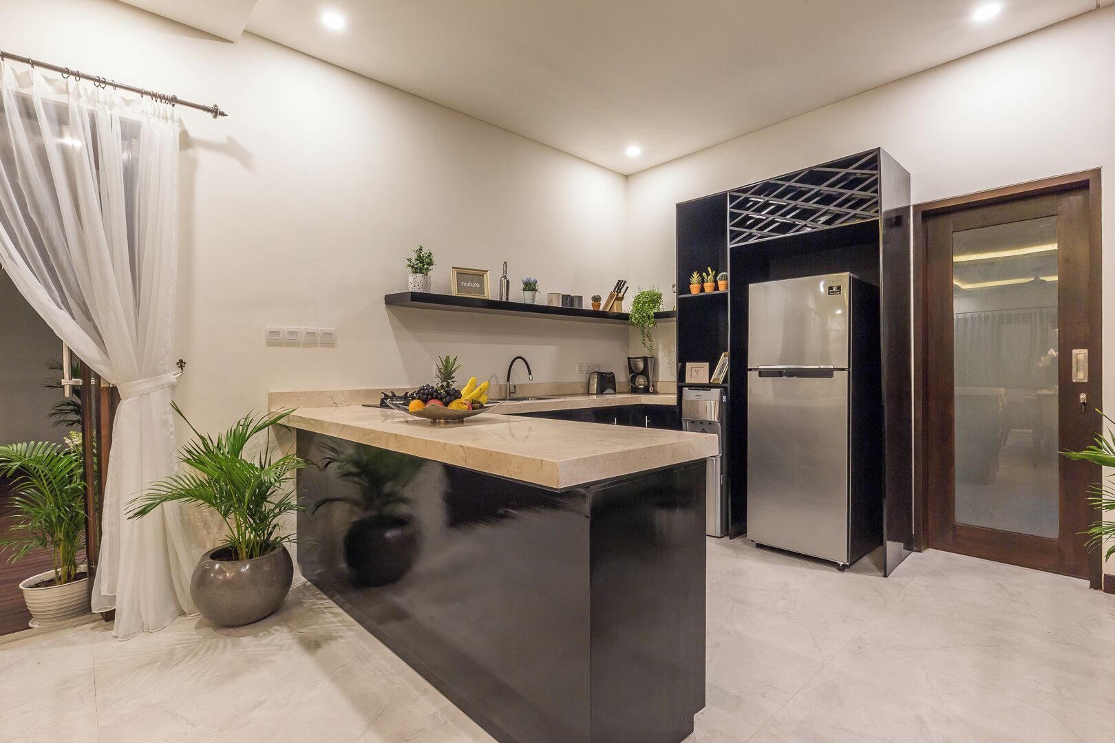 Una cocina moderna con una isla central, un refrigerador integrado y una pared de acento oscura.