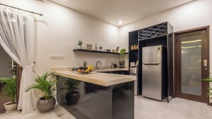 A modern kitchen with a central island, a built-in refrigerator, and a dark accent wall. - Villa Azura Seminyak (Badung)