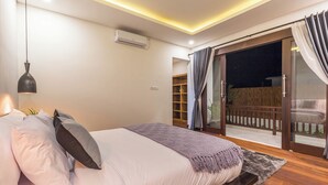 A bedroom with a bed, bedside lamp, air conditioning unit, and a view of a balcony. - Villa Azura Seminyak (Badung)