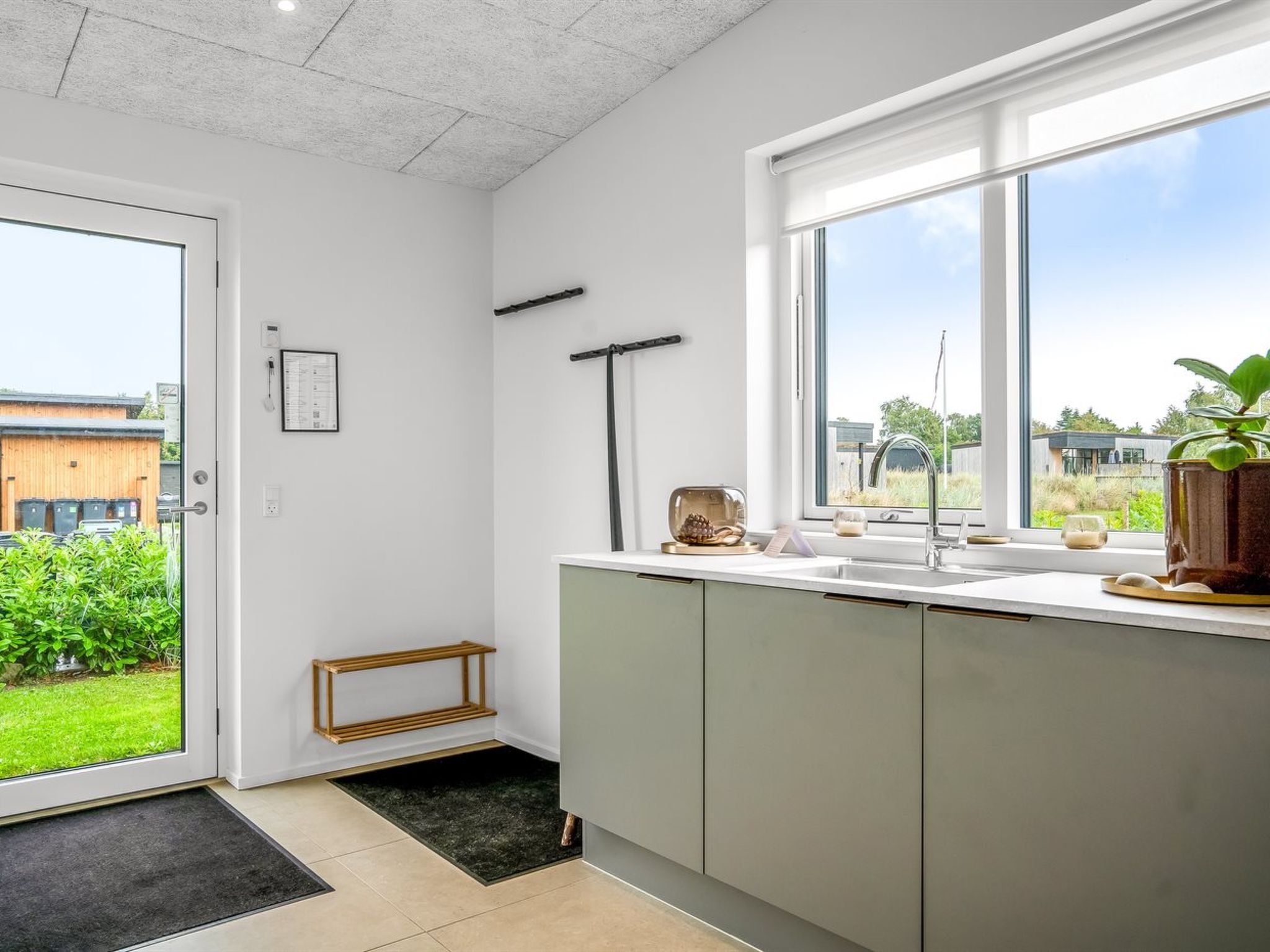 Een moderne keuken met een groot raam, een inbouwspoelbak en een klein opstapje naar de deur.