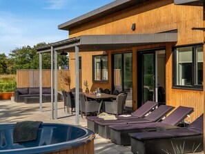 Een modern buitenterras met een eethoek, loungestoelen en een hottub.