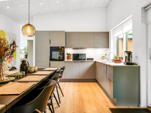 Eine moderne Küche mit einer zentralen Kochinsel, Holzboden und einem Essbereich mit Stühlen.