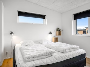 Una camera da letto con un letto, due lampade da comodino, una finestra con vista e un piccolo ripiano con una pianta.