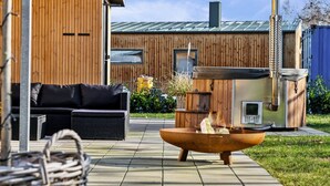 Moderni ulkotila, jossa on patio, nuotiopaikka, sohva ja puinen seinä.
