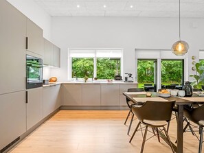 Una cucina moderna con un'isola grande, elettrodomestici integrati e ampie finestre vista su spazi verdi.