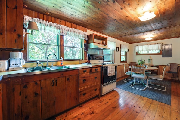A wooden cabin interior with a kitchen, dining area, and a fireplace.