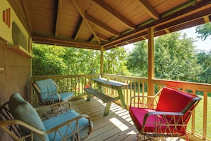 A covered outdoor deck with wooden furniture and a picnic table.