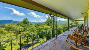 Ein Balkon mit Blick auf eine gebirgige Landschaft, Holzschaukelstühle und ein Fliesenboden.
