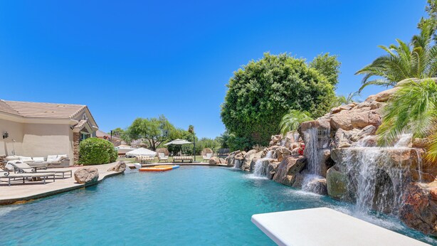 A swimming pool with a waterfall feature, lounge chairs, and a building with a tiled roof. - 3 Mi to Dtwn Gilbert! Apt w/ Shared Poolside Oasis (Gilbert)