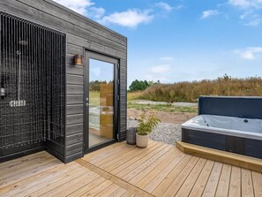 A modern outdoor hot tub area with a wooden deck, a glass door leading to a room, and a view of the surrounding landscape. - "Tayara" - 900m from the sea by Interhome (Glesborg)