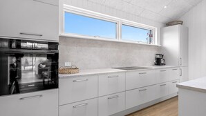A modern kitchen with white cabinetry, a large window, and a visible Siemens appliance.