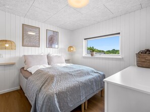 Quarto com cama, janela e mesa de cabeceira.