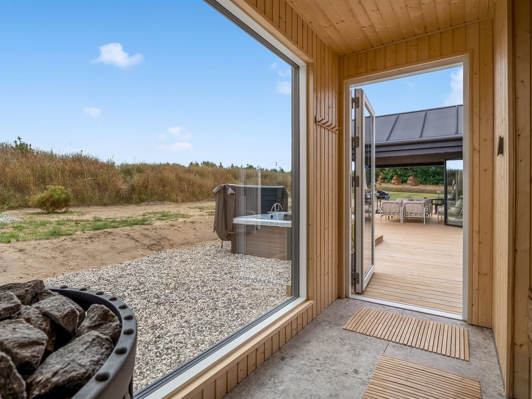 Un interior de madera con un gran ventanal que da a una terraza exterior.
