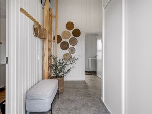 Um corredor com um banco, uma planta em vaso e uma parede decorada com peças circulares de tear.