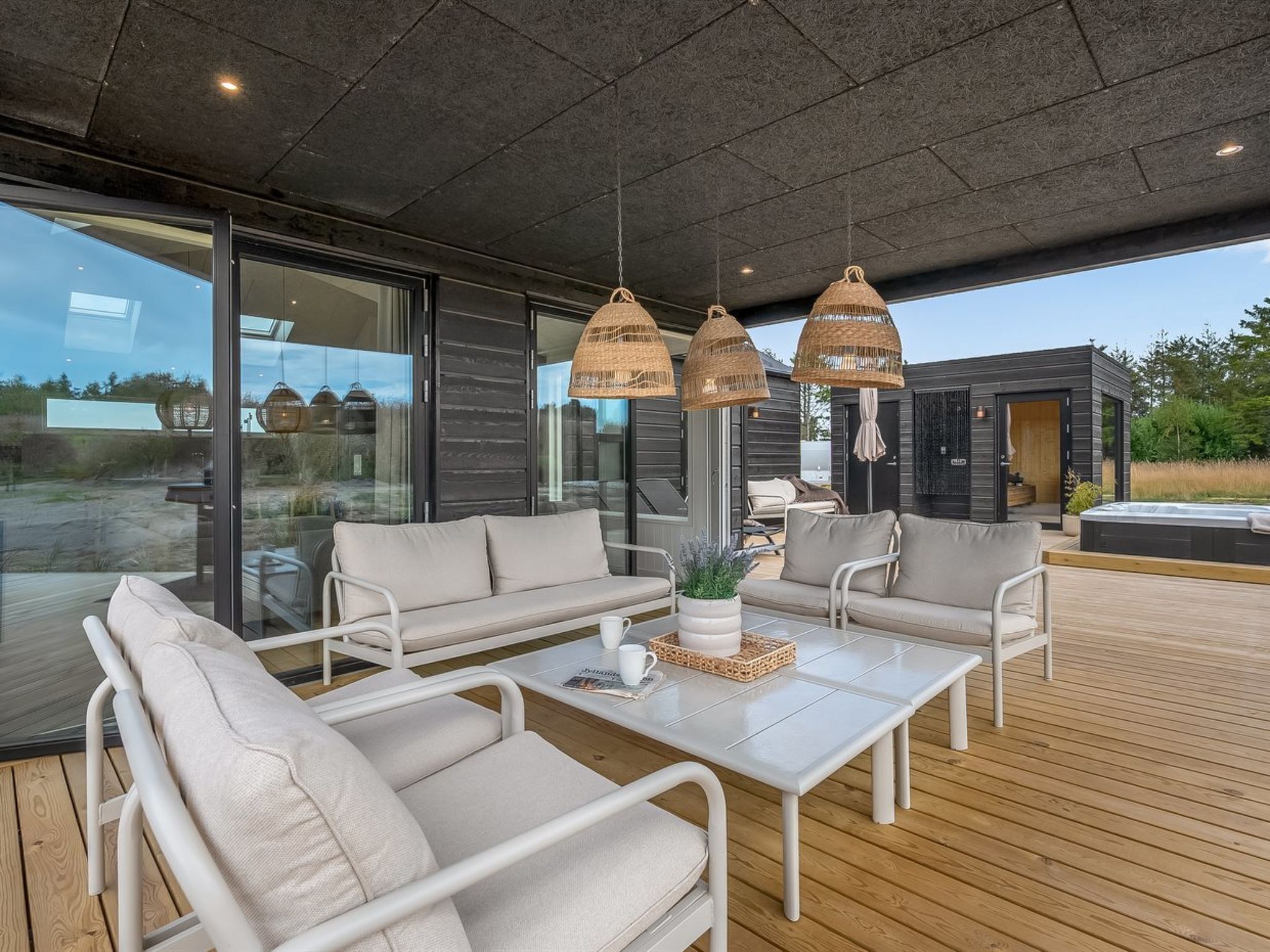 Un espace extérieur moderne, aménagé avec une structure vitrée, une terrasse en bois et un jacuzzi.