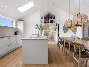 A modern kitchen with a central island, wooden dining table, and pendant lights. - "Tayara" - 900m from the sea by Interhome (Glesborg)