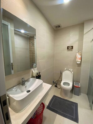Ein modernes Badezimmer mit einem weißen Waschbecken, einer Toilette, einer Dusche und einem Rauchverbot-Schild.