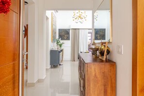 Un couloir avec une porte en bois, une armoire grise et une coiffeuse en bois surmontée d’un globe terrestre et d’une lampe.