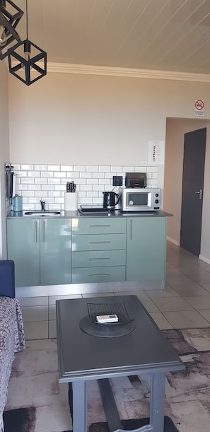 Cocina compacta con microondas, hervidor y armarios.
