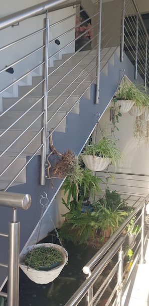 Una escalera con barandillas metálicas y plantas colgantes.