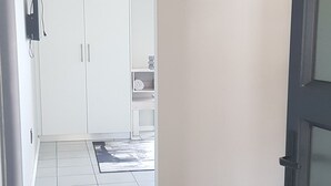 A hallway with a tiled floor, a welcome sign, a geometric pendant light, and a door leading to a room. - Beachfront Accommodation (West Coast District Municipality)