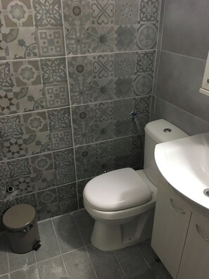 Une salle de bain équipée de toilettes, d’un lavabo et d’une poubelle.