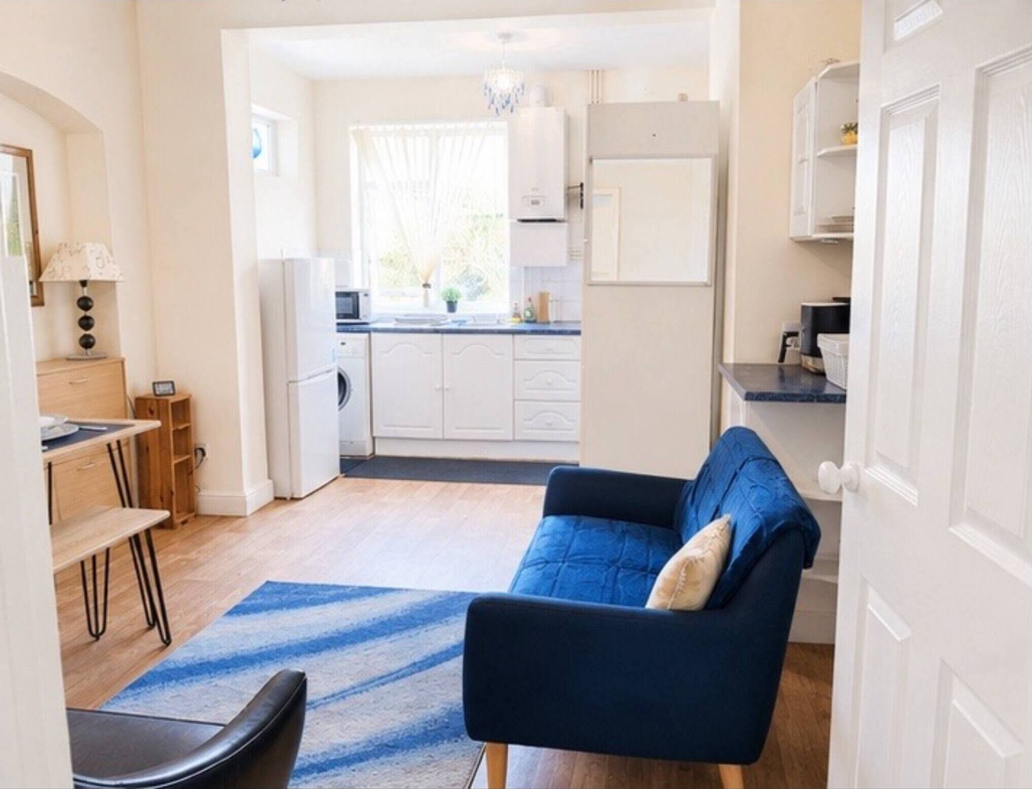 Un espacio habitable compacto con sofá, una mesa de comedor y una kitchenette al fondo.