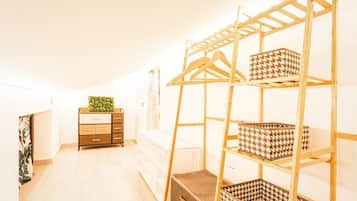Ein Zimmer mit einem Holzkoffer, einer Kleiderstange und einem Stauraum mit gemusterten Körben.