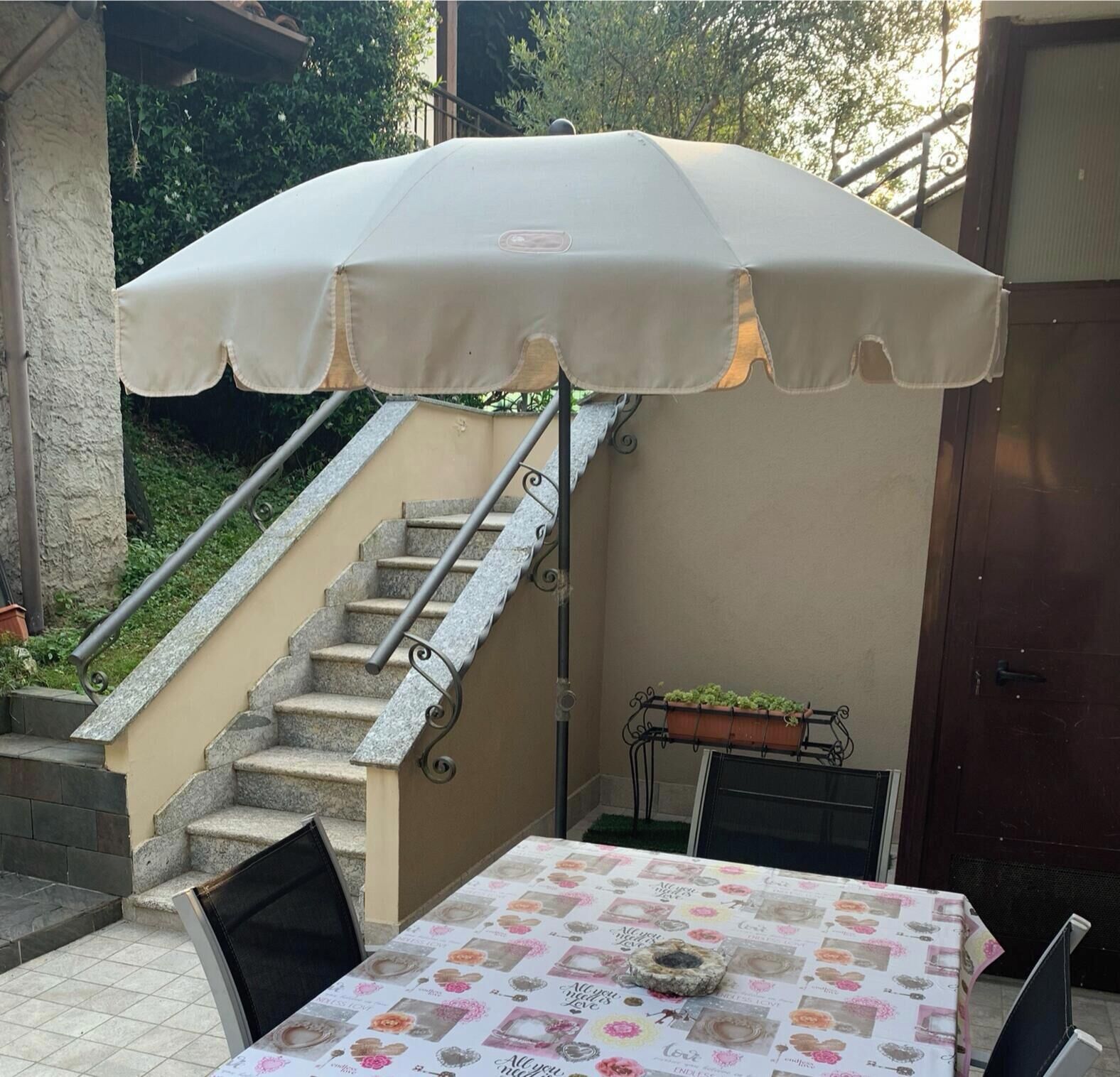 Un espace patio avec une table recouverte d’une nappe, un escalier et une porte.