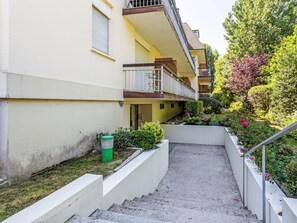 A narrow pathway leading to a building with a balcony, surrounded by greenery and a small garden. - Annabel by Interhome (Houlgate)